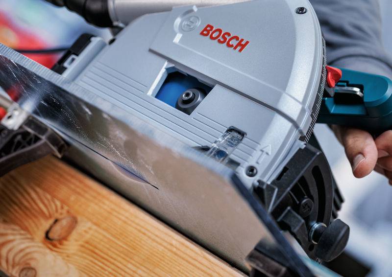 Eine Person benutzt eine Bosch-Kreissäge, um ein Holzbrett zu schneiden, wobei der Fokus auf dem Sägeblatt und dem Holz liegt.