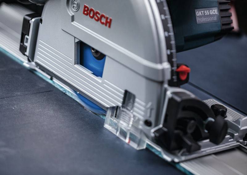 Eine Nahaufnahme einer Bosch-Kreissäge, die ein dunkles Material schneidet, wobei das Sägeblatt, das Markenlogo und ein Teil der Maschine für Präzisionsarbeit zu sehen sind.