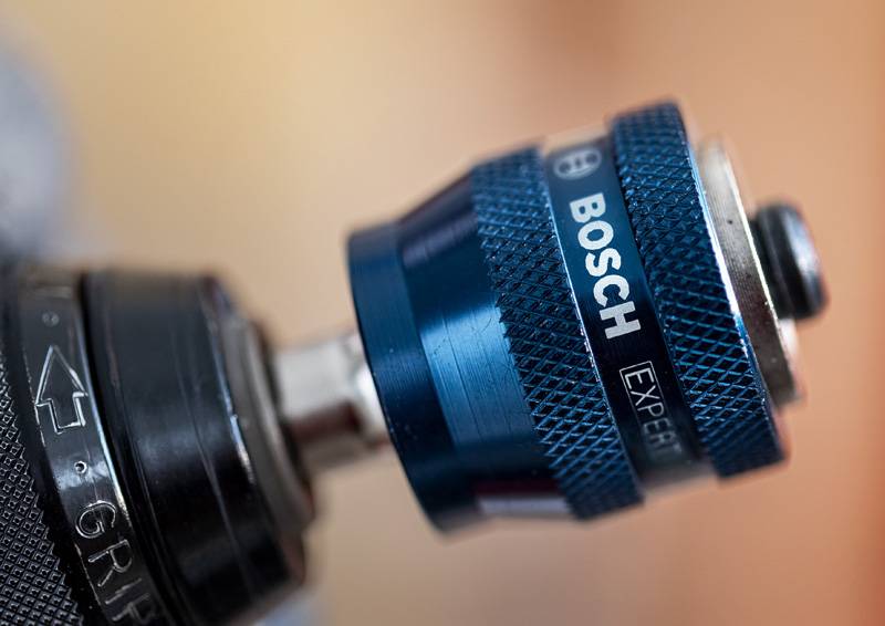 Eine Nahaufnahme einer blauen Bosch-Bohrfutter, die eine strukturierte Griffoberfläche und die Markenbezeichnung "Expert" zeigt, angebracht an einem schwarzen Elektrowerkzeug.