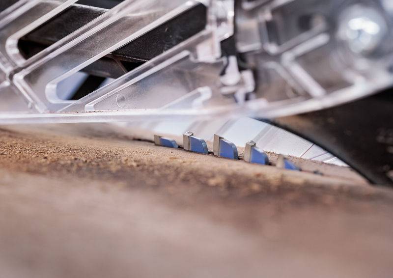 Eine Nahaufnahme einer Kreissägeblatt, das durch eine Holzoberfläche schneidet, wobei die Zähne und die Bewegung des Blattes hervorgehoben werden.