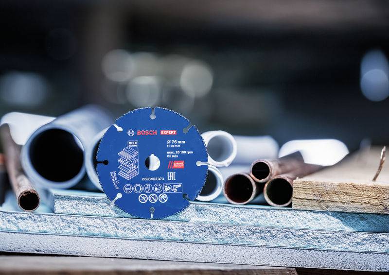 Eine Person, die einen blauen elektrischen Winkelschleifer verwendet, um in eine Wand zu schneiden, trägt schwarze Handschuhe für die Sicherheit.