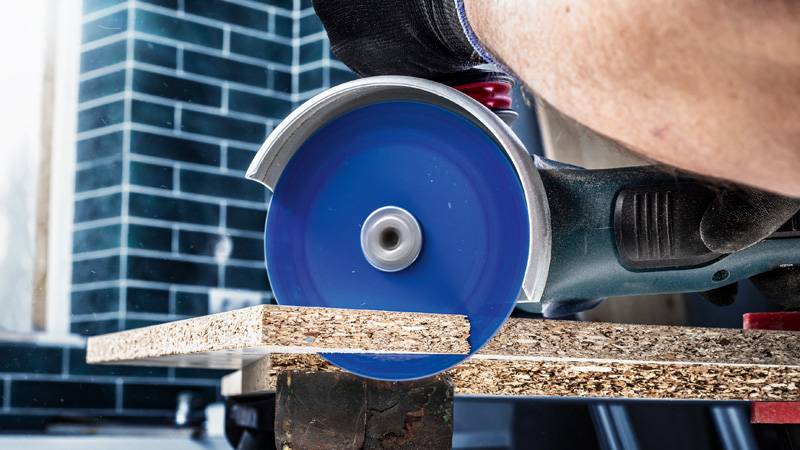 Ein Elektrowerkzeug mit einer blauen Kreisklinge schneidet durch ein Holzbrett und zeigt dabei präzises Schneideverhalten.