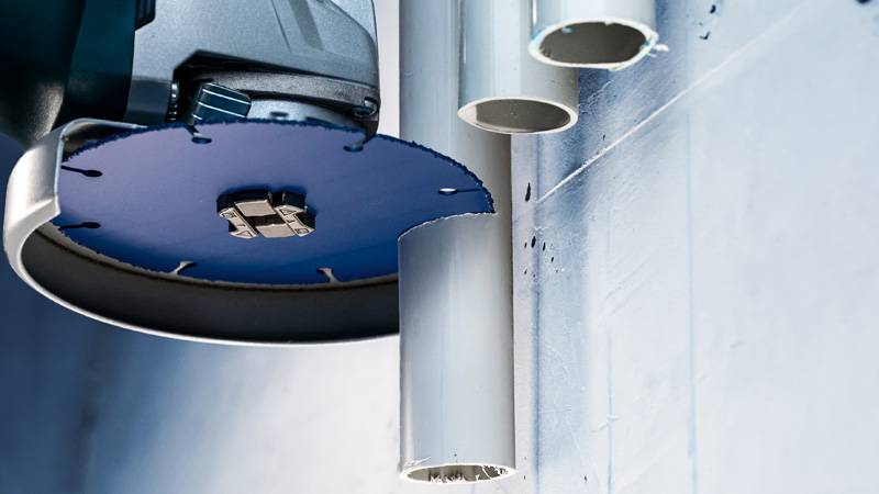 Ein Werkzeug mit einer Kreissägeblatt schneidet durch Kunststoffrohre, die an einer Wand befestigt sind, und zeigt Konstruktionsarbeiten.