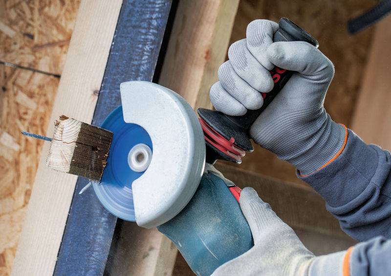 Person, die ein Sägeblatt einer Kreissäge zum Schneiden eines Holzblocks nutzt, während sie Schutzhandschuhe trägt; demonstriert sichere Holzbearbeitungspraxis.