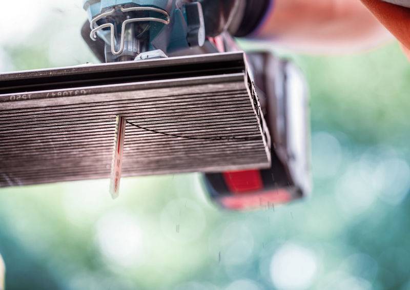 Eine Person nutzt ein Elektrowerkzeug, um ein Metallblech zu schneiden und erzeugt dabei Funken. Der Hintergrund ist unscharf, wodurch die Schneidaktion betont wird.