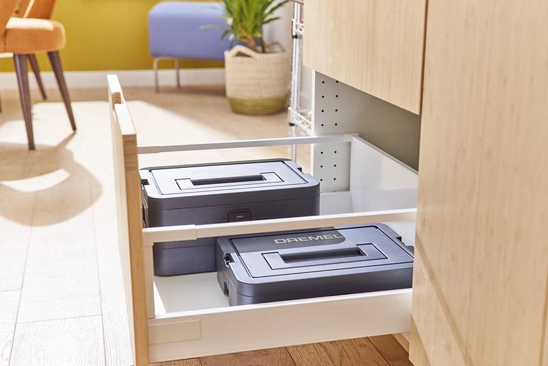 Eine Küchenlade ist offen und zeigt zwei schwarze Aufbewahrungskästen mit Griffen mit der Aufschrift „DREMEL