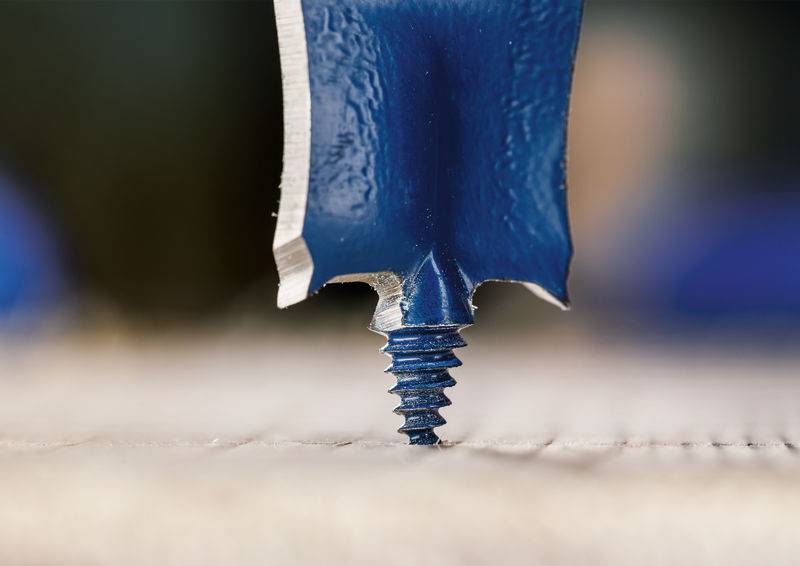 Eine Nahaufnahme einer blauen, flachklingigen Schraubendreherspitze, die in eine Schraube eingreift. Das Bild konzentriert sich auf die präzise Passung der Klinge im Schraubenkopf.