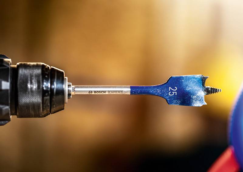 Nahaufnahme eines Bohrers, der an einer Bohrmaschine befestigt ist, mit einem blauen Spatenaufsatz mit der Nummer „25