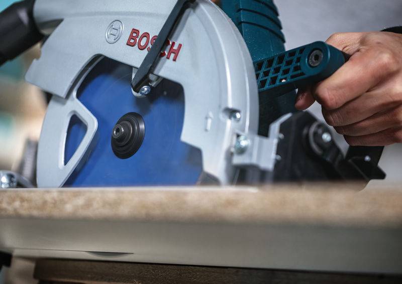 Eine Person, die eine Bosch-Kreissäge zum Holzschneiden verwendet, mit Fokus auf das Sägeblatt und den Griffgriff.
