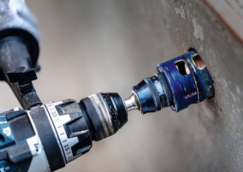 Ein Bohrgerät mit einer Lochsäge schneidet durch eine Betonwand.