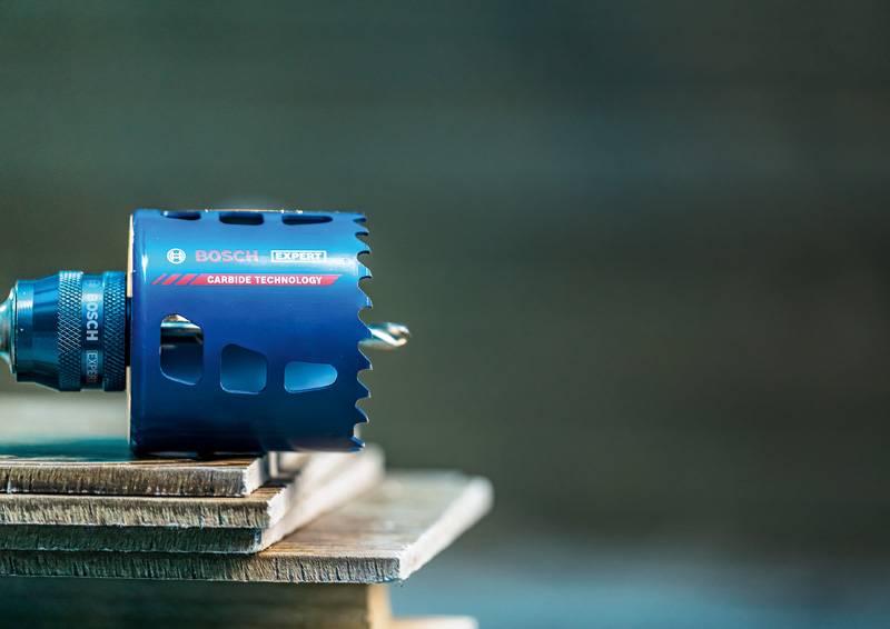 Eine blaue Bosch-Lochsäge mit Hartmetalltechnologie auf einer Holzoberfläche, die ihre Präzision und Haltbarkeit für Schneidaufgaben demonstriert.