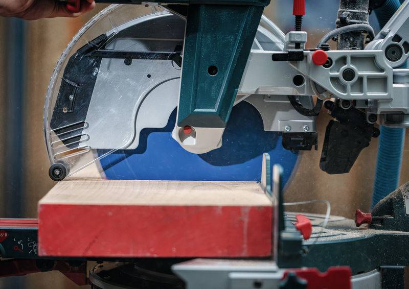 „Eine Kreissäge, die mit Präzision durch Holz auf einer Werkbank schneidet, umgeben von Holzbearbeitungswerkzeugen und -ausrüstung.