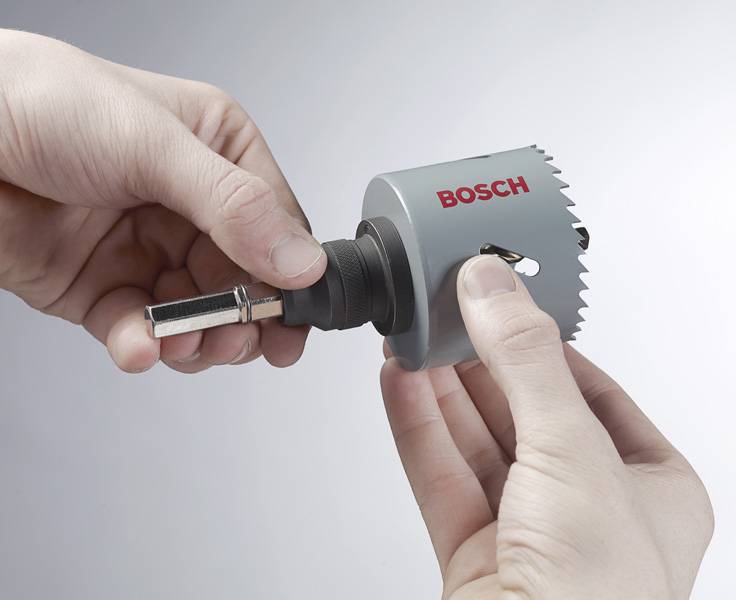 Eine Person setzt eine Bosch-Lochsäge zusammen und richtet einen Bohrer an der Befestigungsstelle der Säge aus.