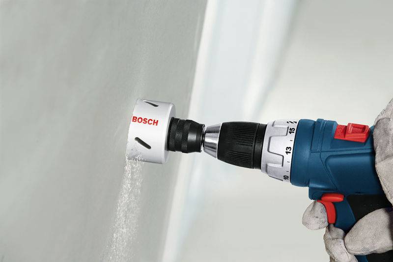 „Eine Hand benutzt einen Bosch Elektroschrauber, um ein rundes Loch in eine Wand zu schneiden.