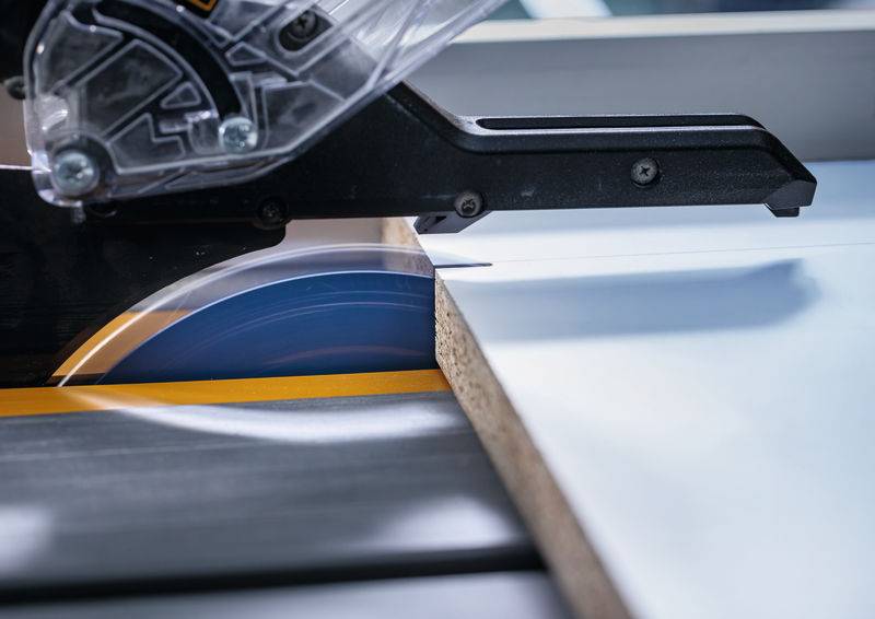 Nahaufnahme einer Kreissäge, die durch ein Holzstück schneidet, wobei Präzision und Details in einer Werkstattumgebung gezeigt werden.