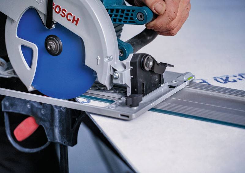 Eine Person verwendet eine Bosch-Kreissäge, um ein Materialblatt zu schneiden, wobei sie präzise Schneidetechnik und Werkzeuganwendung demonstriert.