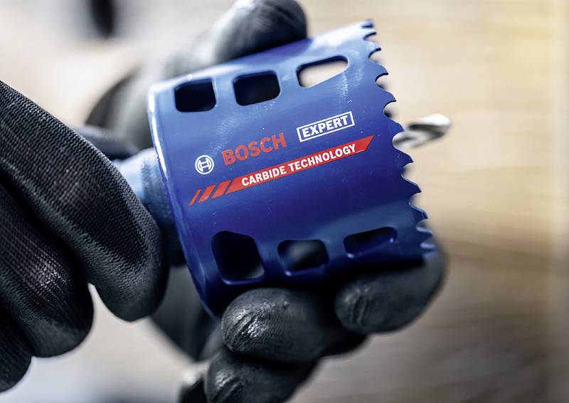 Eine behandschuhte Hand hält eine Bosch Expert Lochsäge mit Hartmetalltechnologie, die für präzises Bohren konzipiert ist.