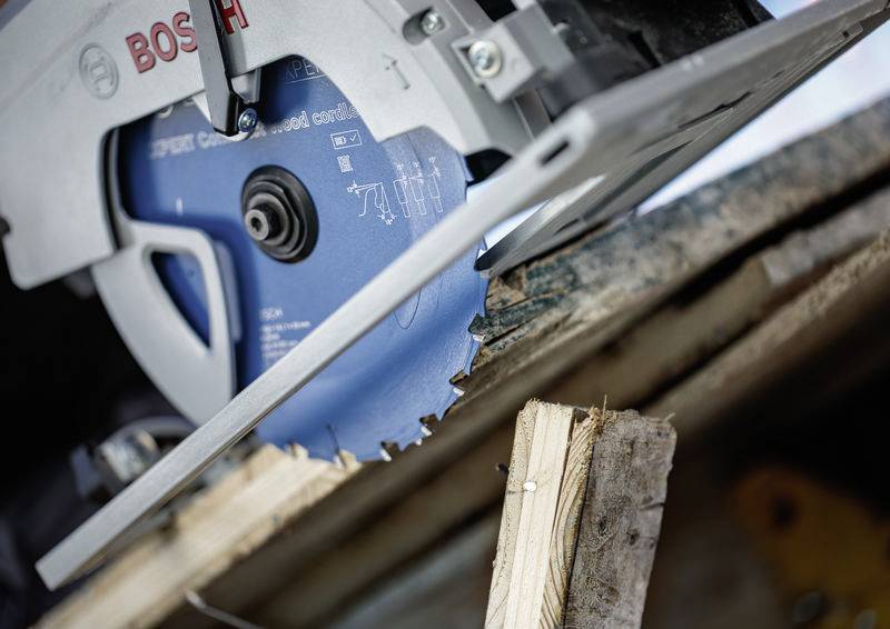 Eine Kreissäge mit einem blauen Blatt schneidet in einem Winkel durch Holzbretter. Die Säge ist mit der Marke „Bosch