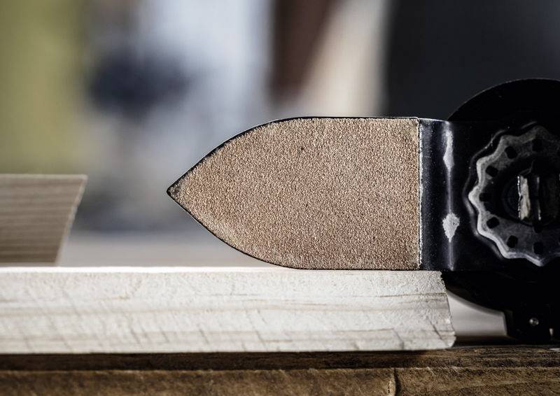 Eine Nahaufnahme eines Schleifwerkzeugs, das die Kante eines Holzbretts glättet und die Präzision in der Holzbearbeitung hervorhebt.