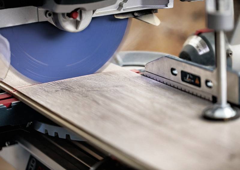 Eine Kreissäge mit blauem Blatt schneidet durch ein Holzbrett und demonstriert Präzision bei der Holzbearbeitung und den Gerätegebrauch.