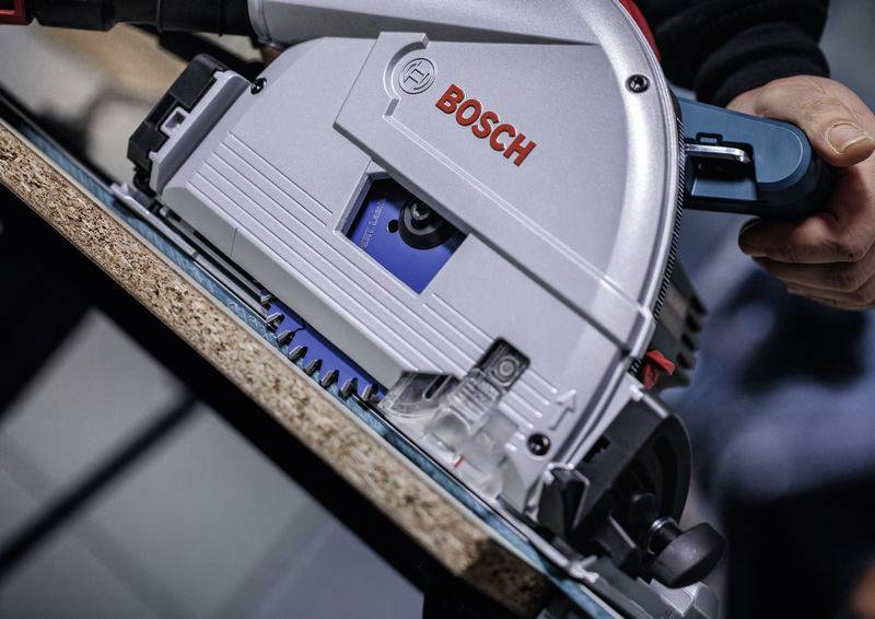 Eine Person verwendet eine Bosch Kreissäge zum Durchschneiden eines Holzbretts und zeigt nahaufnahmedetails des Werkzeugblatts und des Griffs.