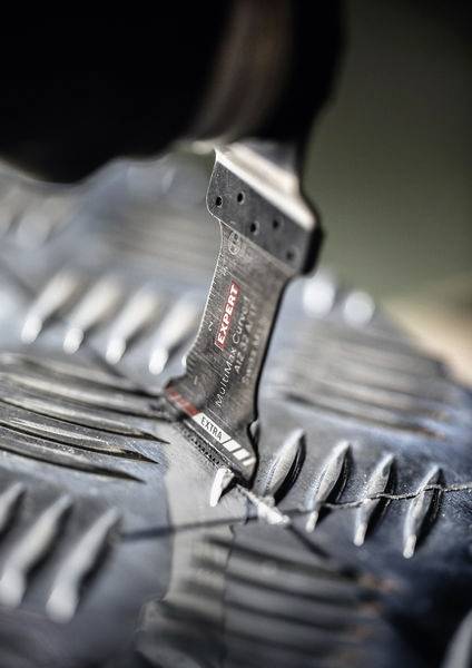 Eine Multitool-Klinge schneidet mit Präzision durch eine strukturierte Oberfläche und zeigt ihre Schärfe und Nützlichkeit für detaillierte Arbeiten.