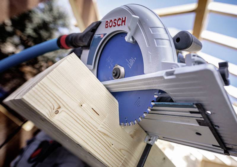 Eine Kreissäge mit einem blauen Blatt schneidet durch ein Holzbrett. Die Säge ist mit der Marke 