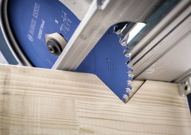 Eine Kreissägeblatt schneidet durch ein Stück Holz, zeigt eine Nahaufnahme der scharfen Zähne und des Holzfasernmusters.