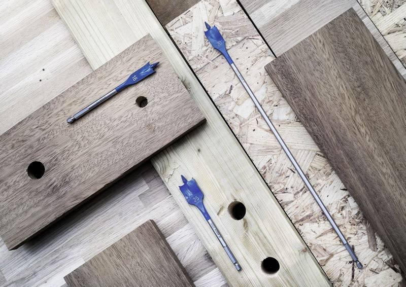 Holzbretter mit gebohrten Löchern, auf denen drei Schaufelbohrmesser in verschiedenen Größen platziert sind.