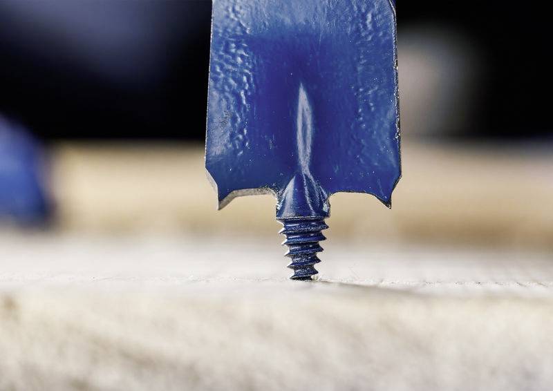Eine Nahaufnahme eines blauen Bohrers, der in eine Holzoberfläche eindringt, wobei die Spitze und die Schneidkanten vor einem unscharfen Hintergrund hervorgehoben werden.
