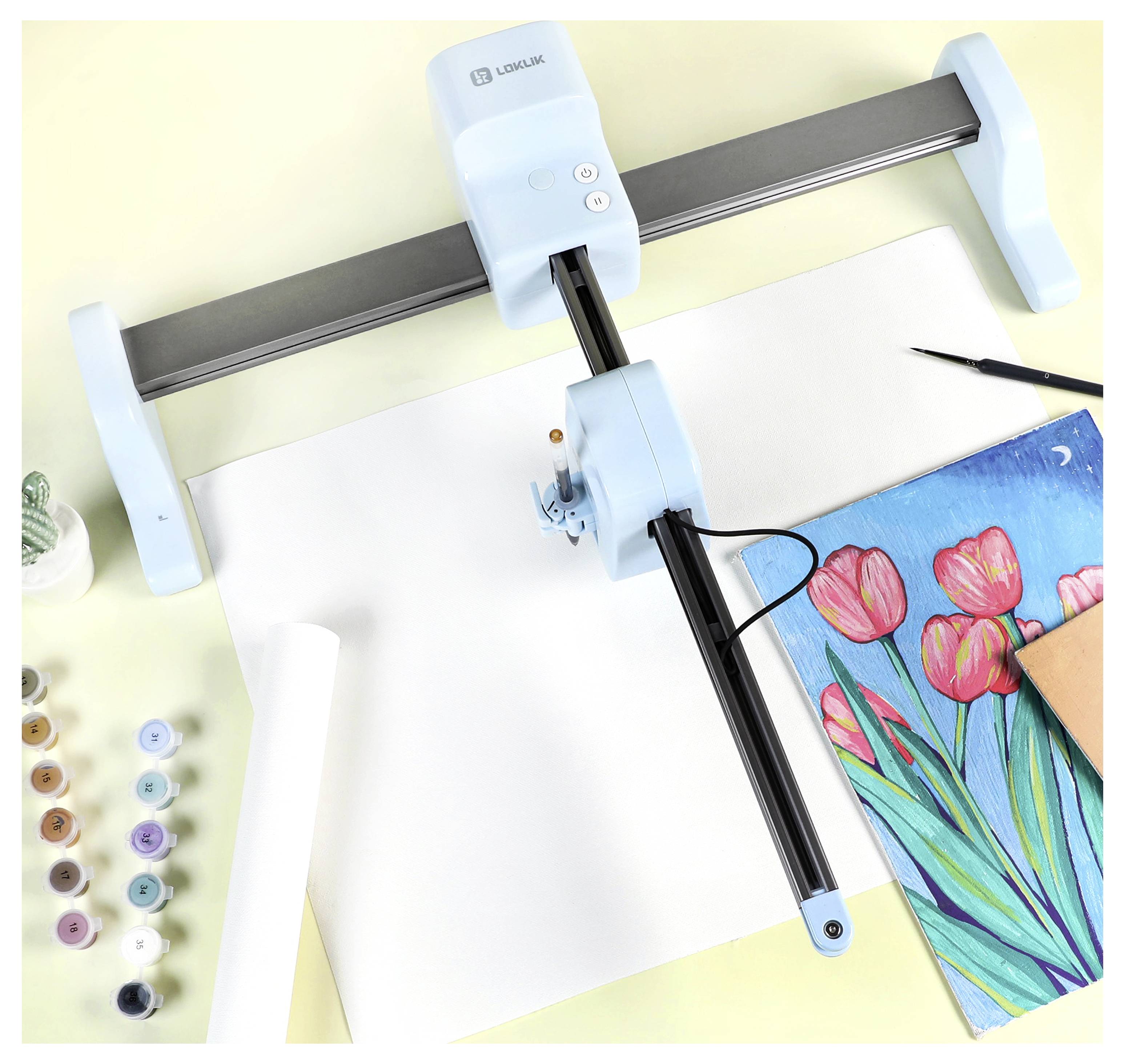 Eine Zeichenmaschine, die über einem leeren Blatt positioniert ist, mit einem fertigen Kunstwerk aus rosa Tulpen und Kunstbedarf wie Farben und Pinseln in der Nähe.