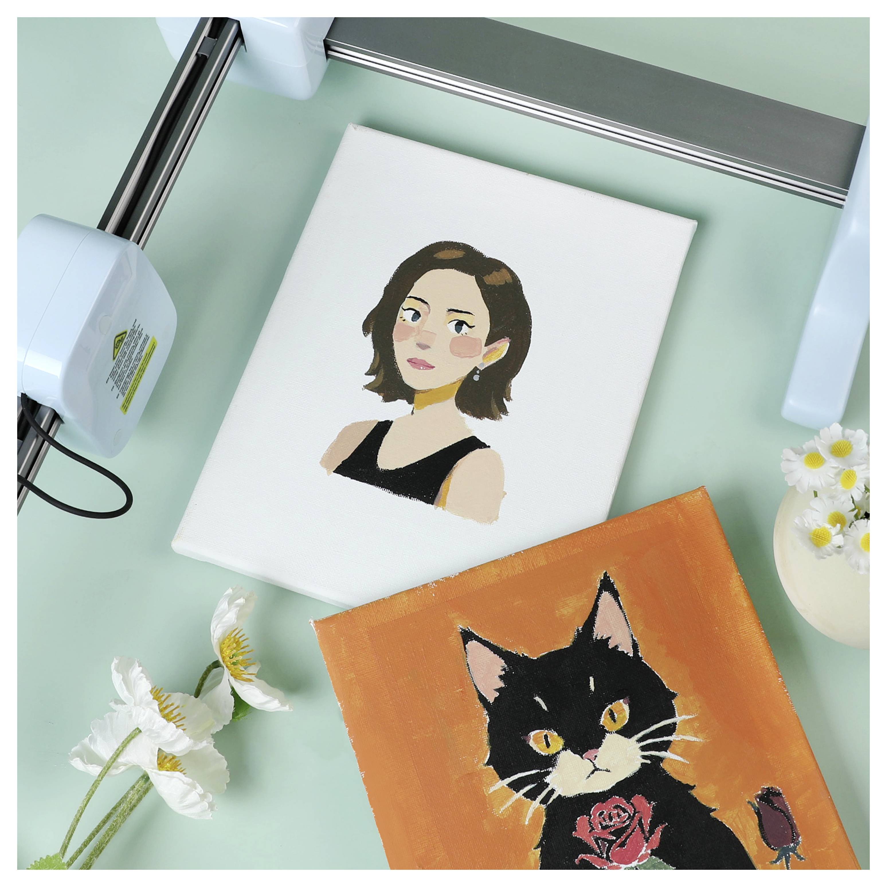 Eine Leinwand mit einem Gemälde einer Frau mit kurzem dunklem Haar in schwarzem Oberteil; eine weitere Leinwand zeigt eine schwarze Katze mit einer Rose auf orangefarbenem Hintergrund.