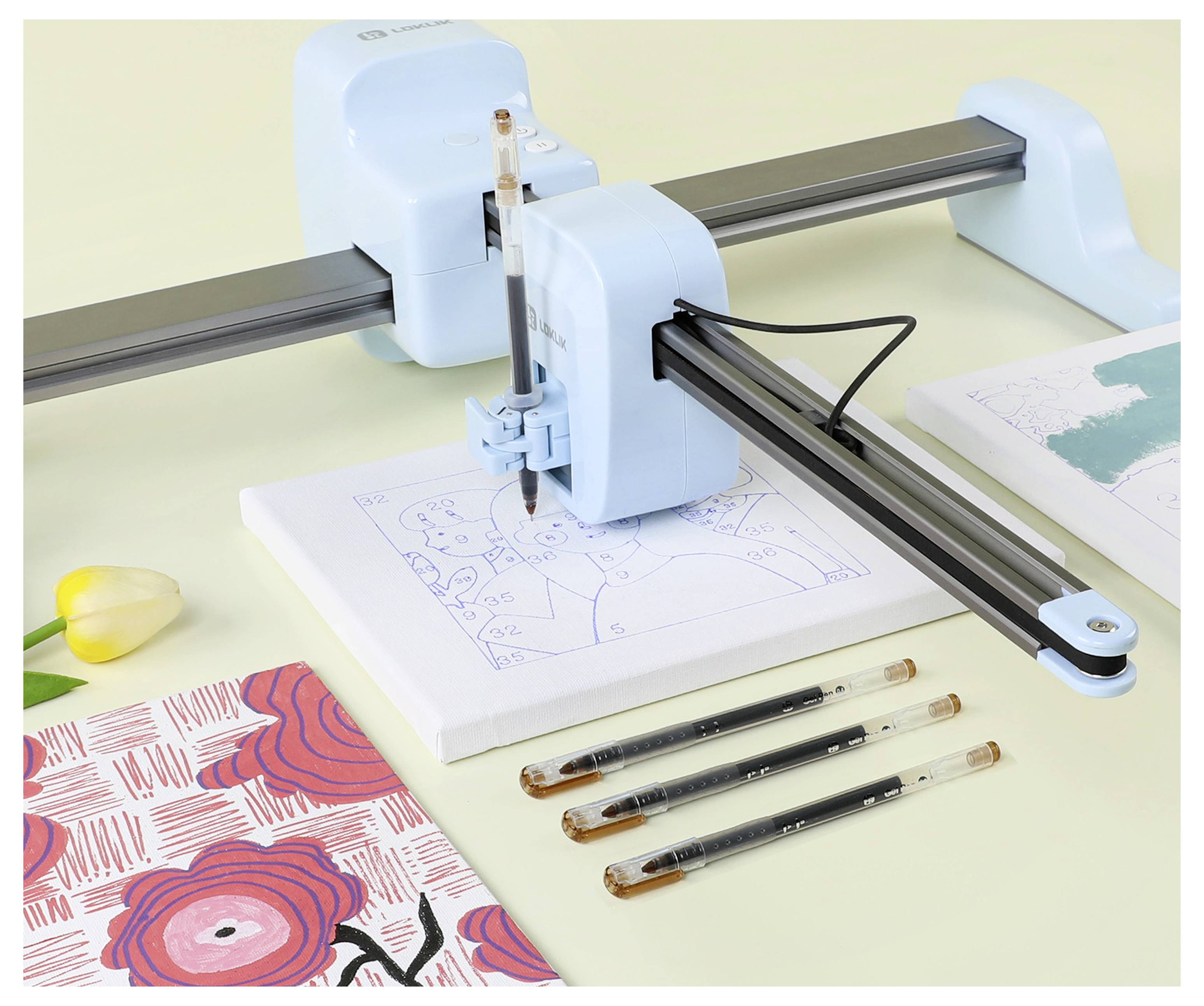 Eine Zeichenmaschine, die eine Illustration von zwei Personen auf einer Leinwand mit Stiften skizziert, mit einem Blumenmusterbuch in der Nähe auf einem Tisch.