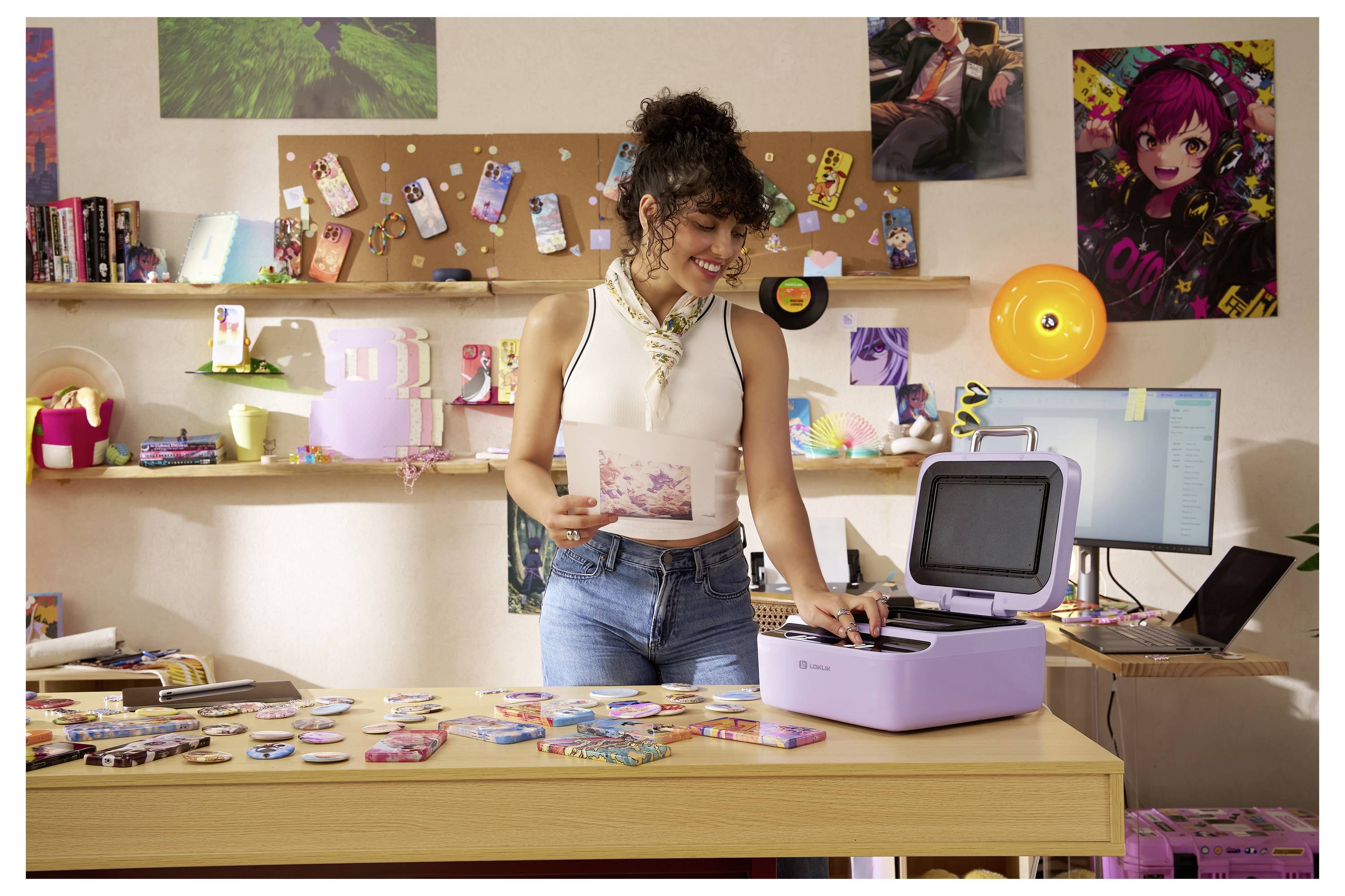 Eine Frau in einem dekorierten Zimmer legt ein Foto in einen lilafarbenen, kompakten Kodak Mini Shot 3 Retro-Drucker auf einem Schreibtisch mit gedrucktem Material.