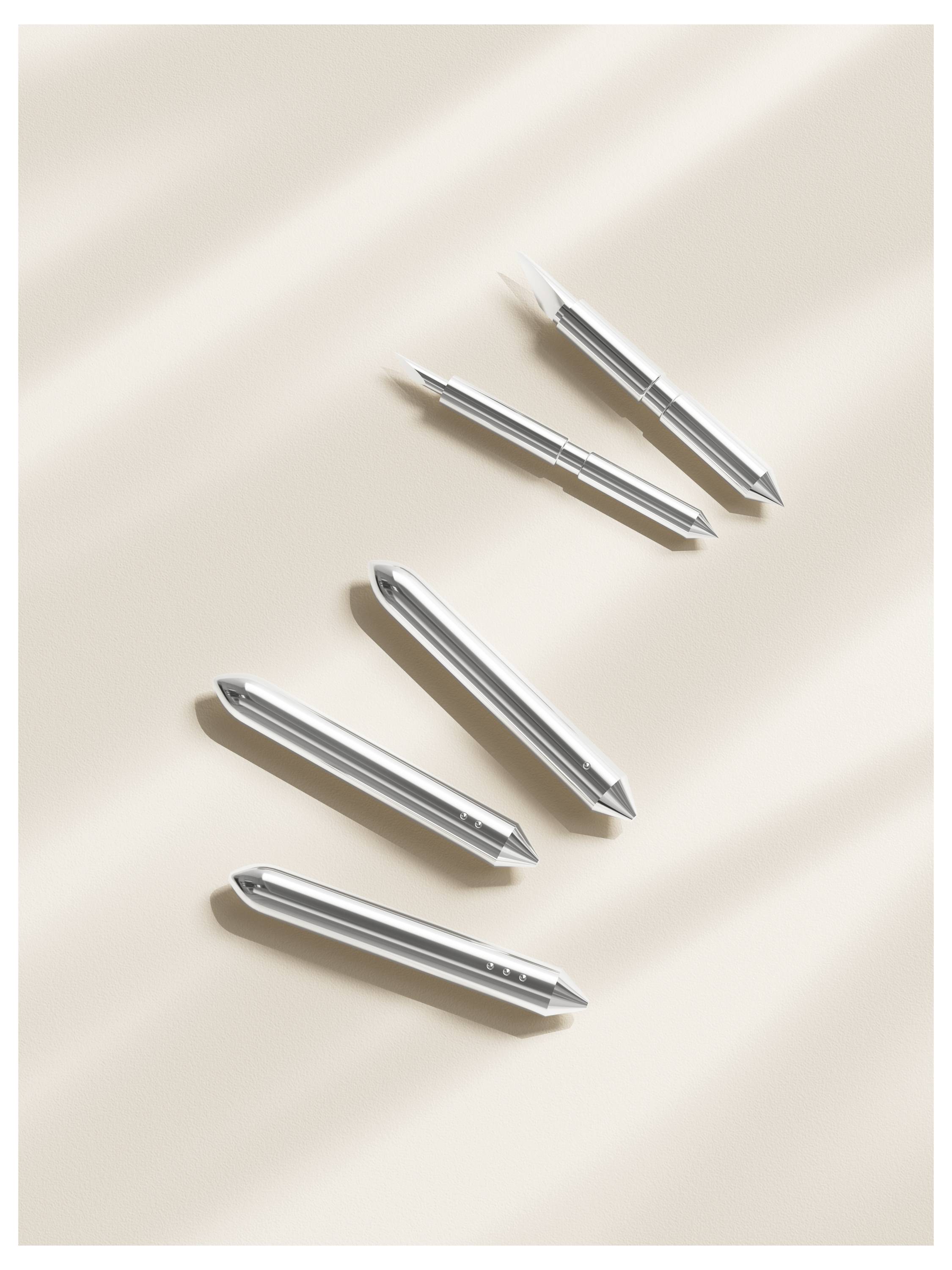 Fünf silberne metallische Stifte diagonal auf einer beigen Oberfläche mit weichen Schatten angeordnet.