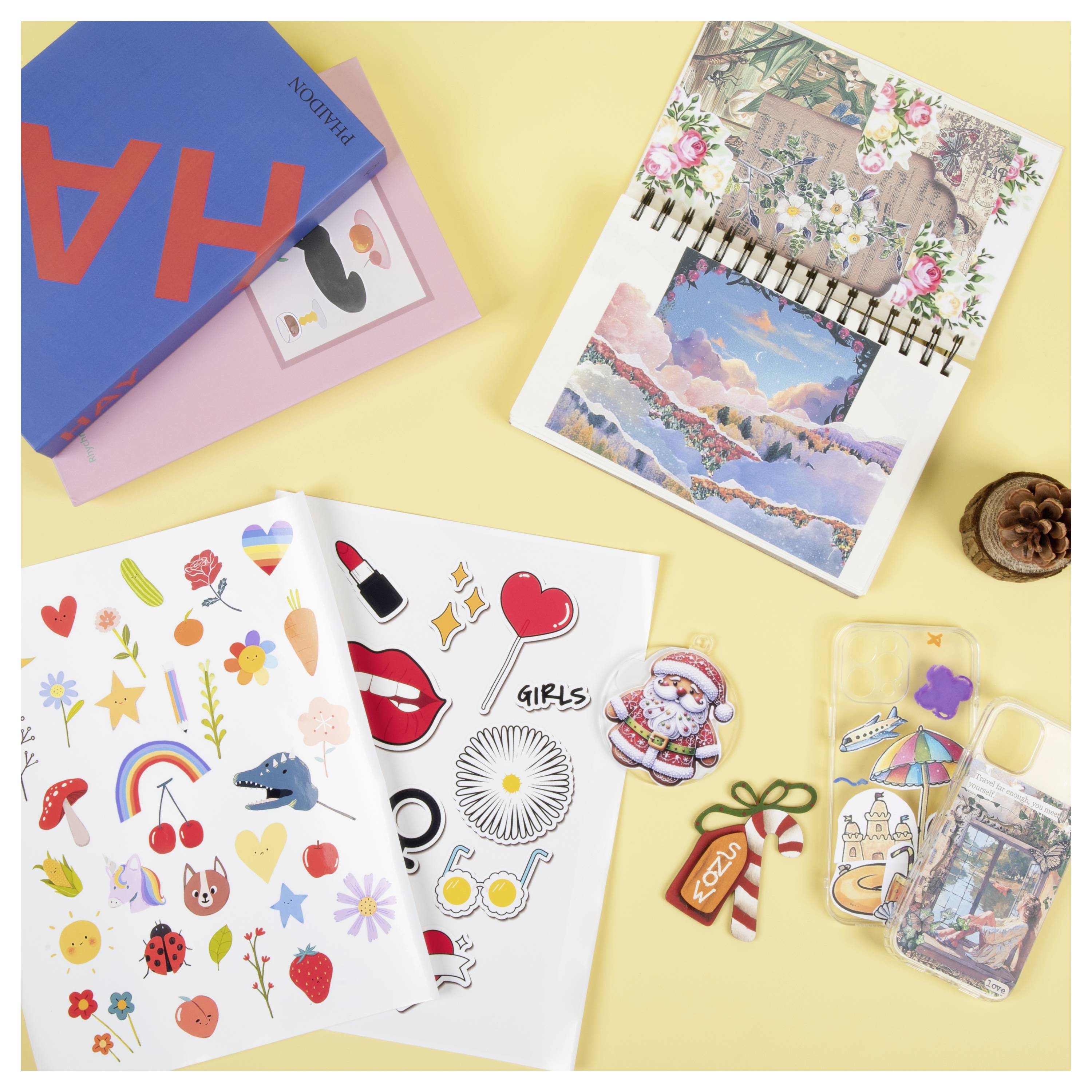 Aufkleber, Notizbücher und Handyhüllen mit bunten Designs sind auf einem gelben Hintergrund angeordnet.