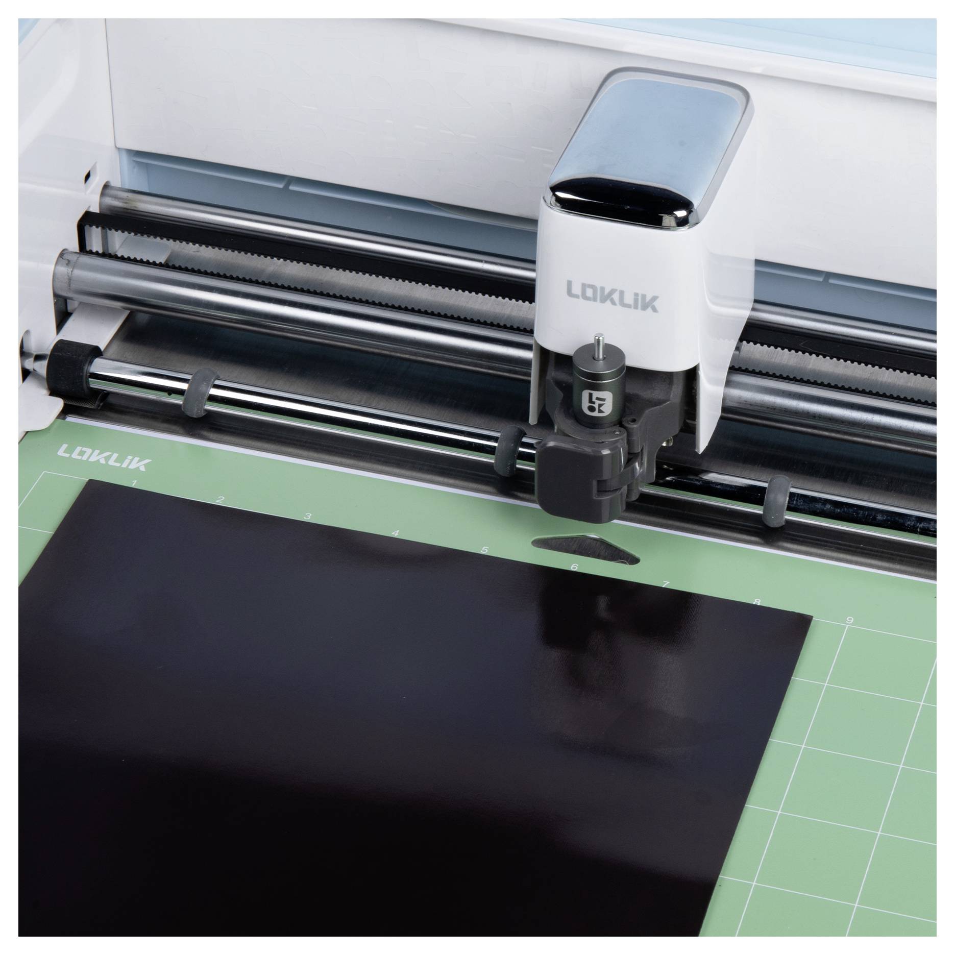 Eine Schneidemaschine schneidet präzise ein schwarzes Blatt auf einer grünen Schneidematte zu.