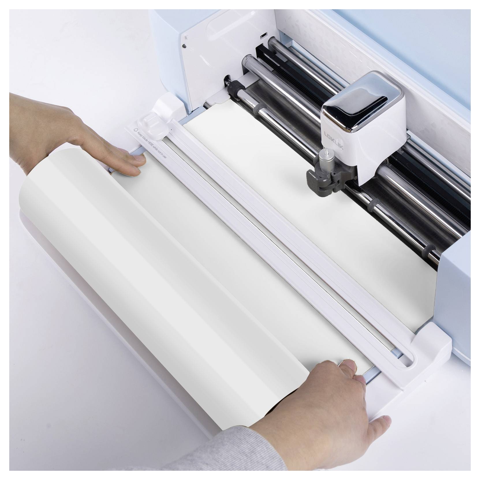 Eine Person lädt ein Blatt weißes Material in eine Schneidemaschine, um sich auf eine präzise Schneidaufgabe vorzubereiten.