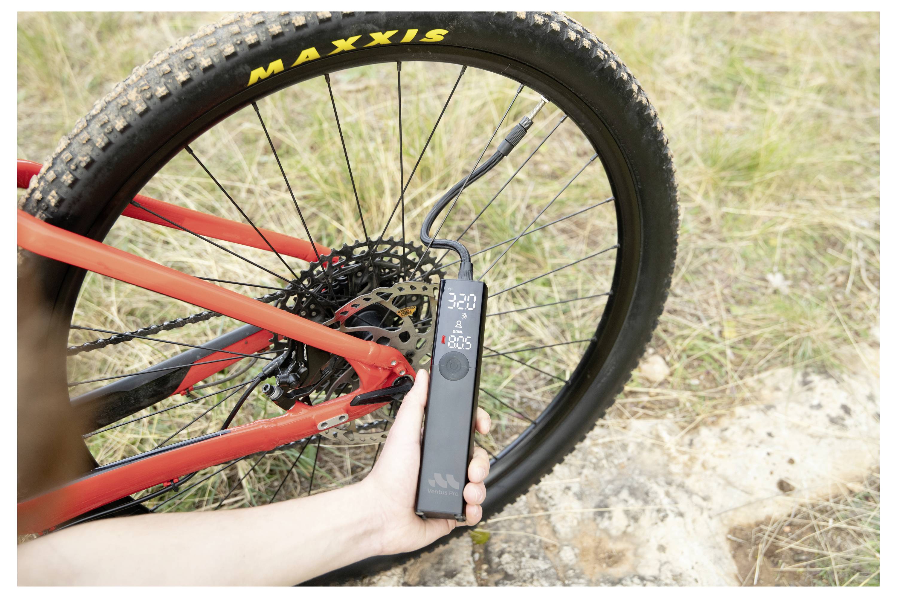 Tragbares digitales Druckmessgerät, das den Druck eines Mountainbike-Reifens in der Nähe des Hinterrads und der Scheibenbremse im Freien misst.