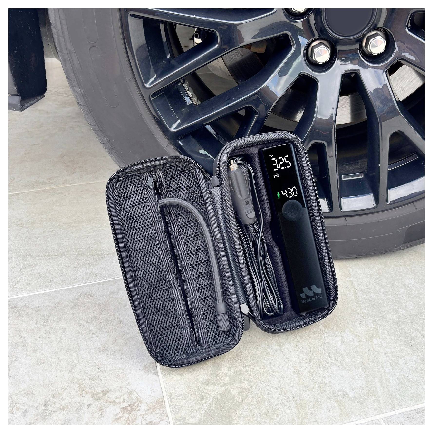 Tragbarer Reifenaufpumpkit, der neben einem Autolad geöffnet ist, zeigt die Pumpe, den Schlauch und die digitale Druckanzeige.