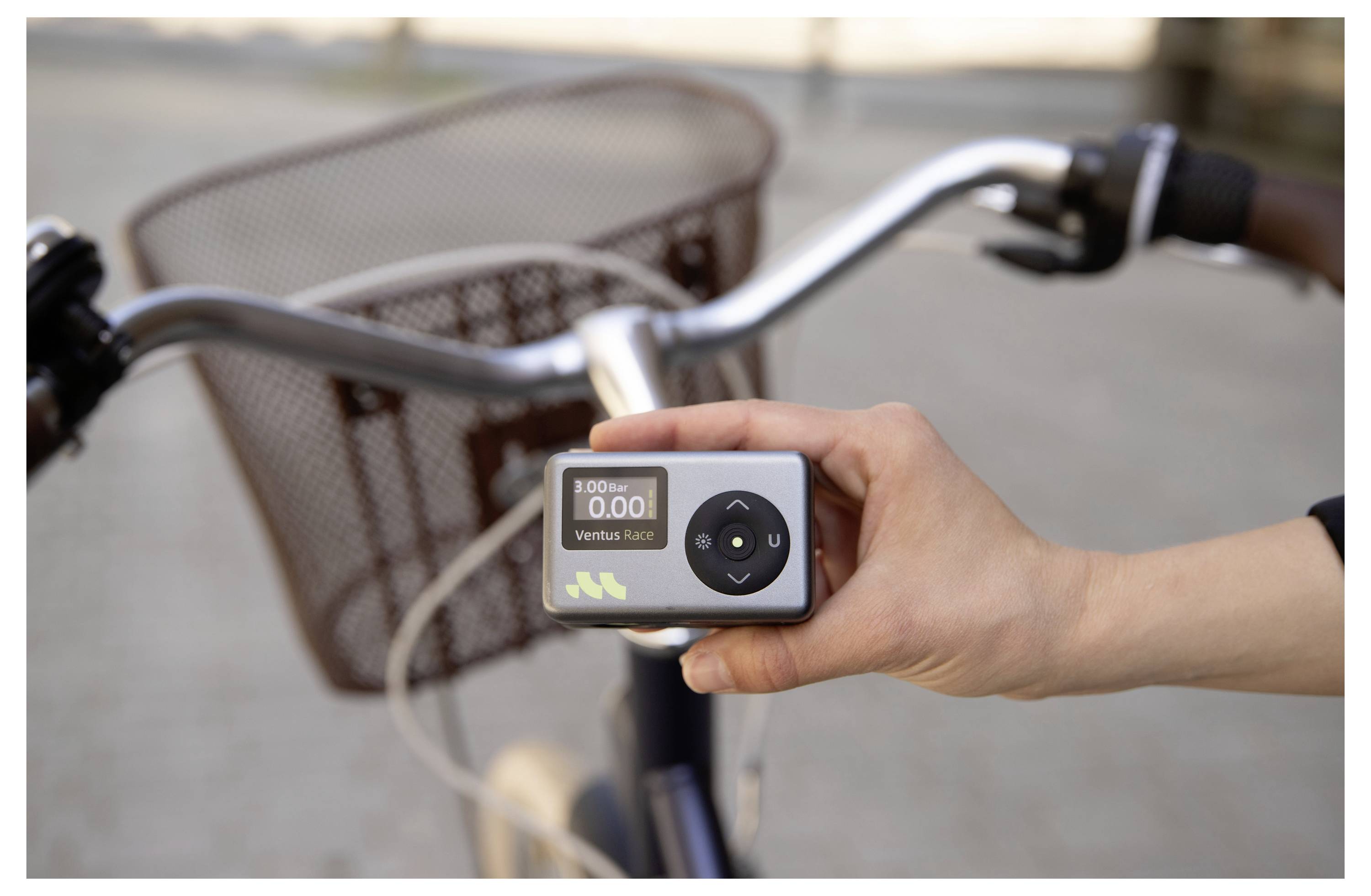 Eine Hand hält ein Fahrrad-Tachometer, das 
