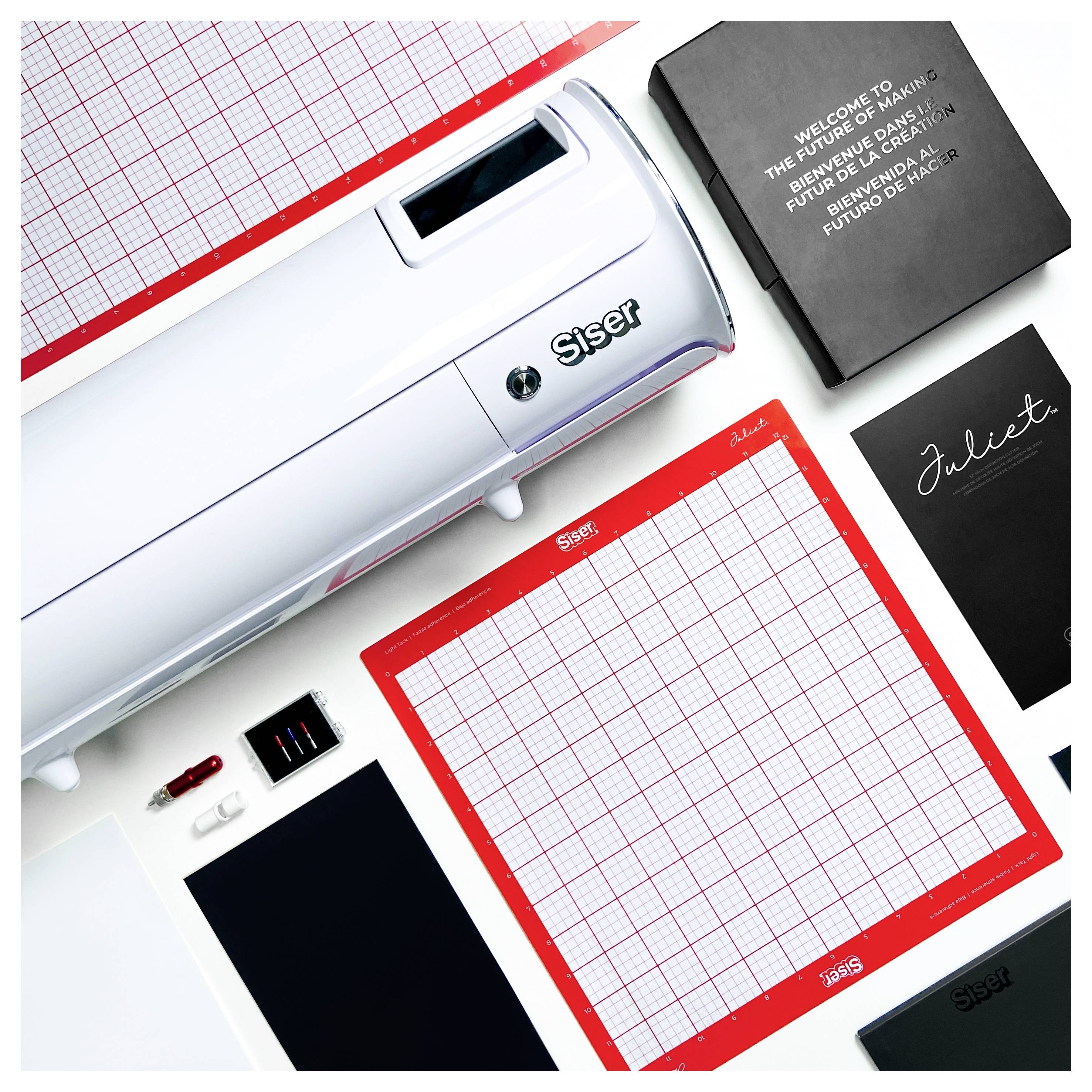 Ein Bastelarbeitsplatz mit einer Schneidemaschine, drei rot-weiß gestreiften Schneidematten mit der Aufschrift „Siser