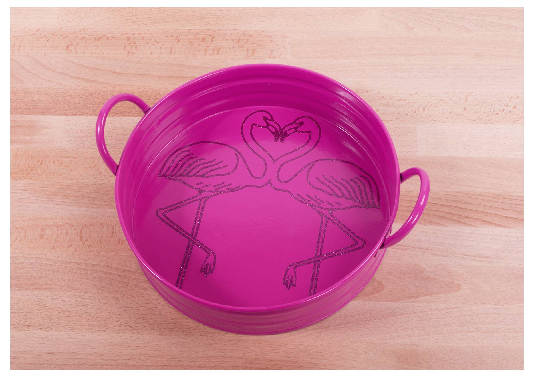 Ein rosa Metalltablett mit zwei Flamingos, die sich gegenseitig zugewandt sind und mit ihren Hälsen und Köpfen eine Herzform bilden. Das Tablett hat seitliche Griffe.