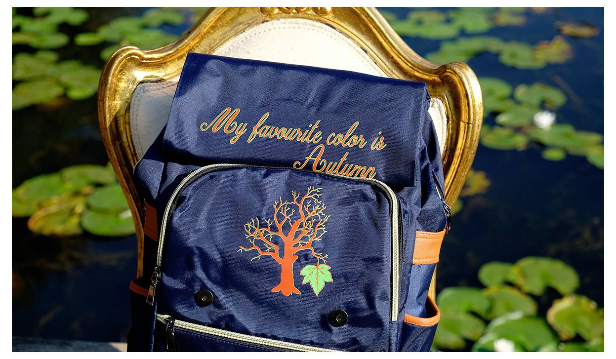Ein marineblauer Rucksack mit der in Orange bestickten Aufschrift „Meine Lieblingsfarbe ist Herbst