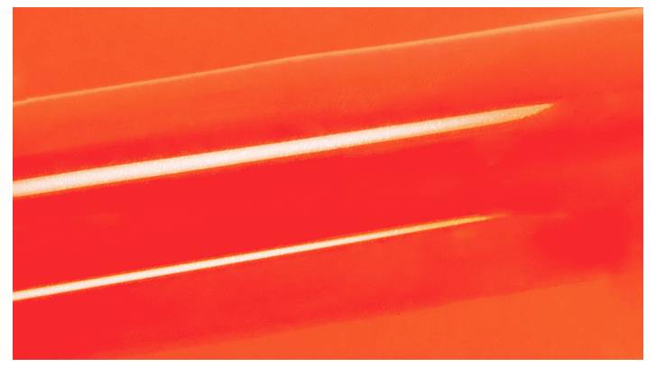 Eine Nahaufnahme eines leuchtend rot-orangefarbenen zylindrischen Objekts mit glatter Textur, das Licht reflektiert, vor einem entsprechenden Hintergrund.