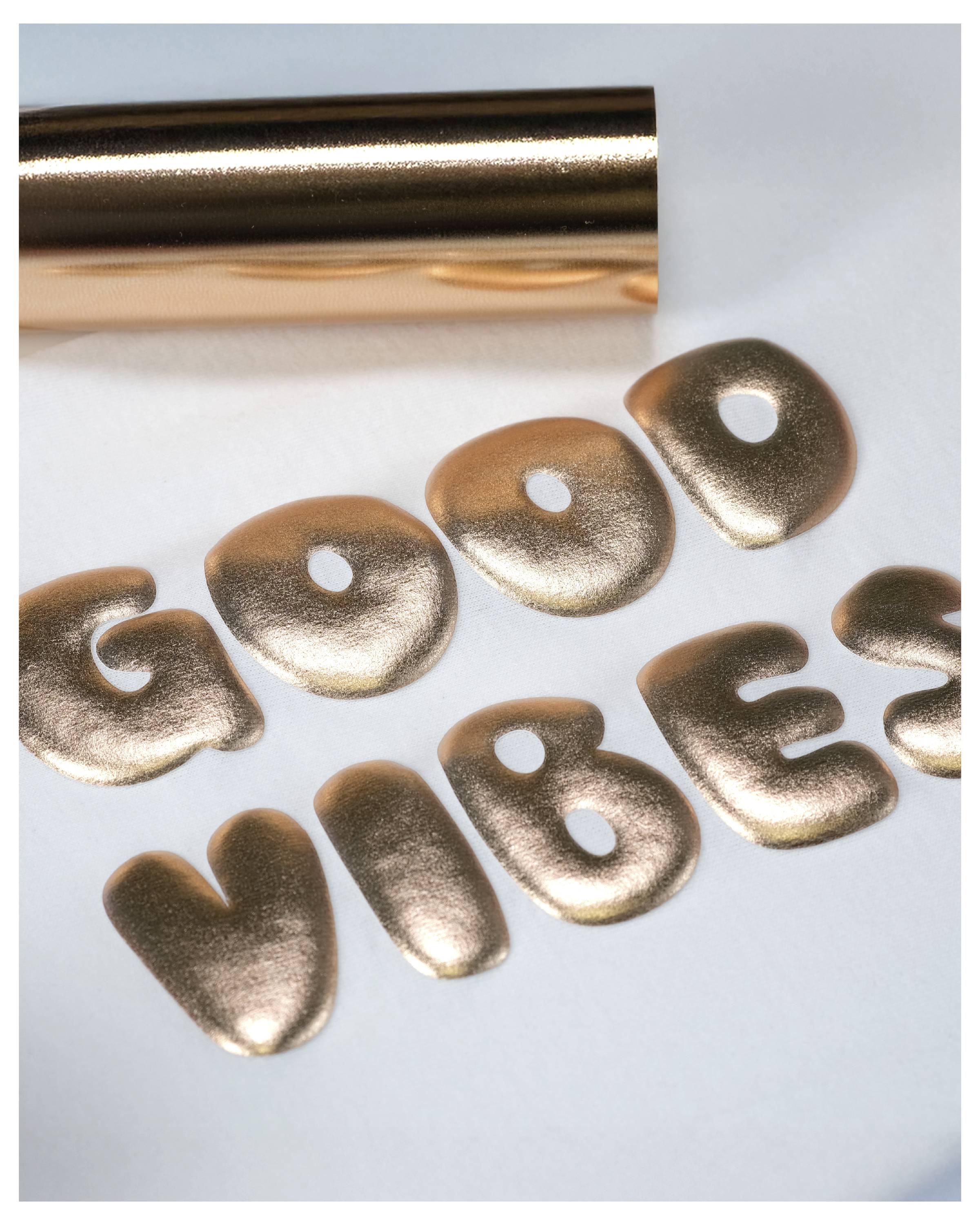 Das Bild zeigt goldene metallische Buchstaben, die die Worte „GOOD VIBES