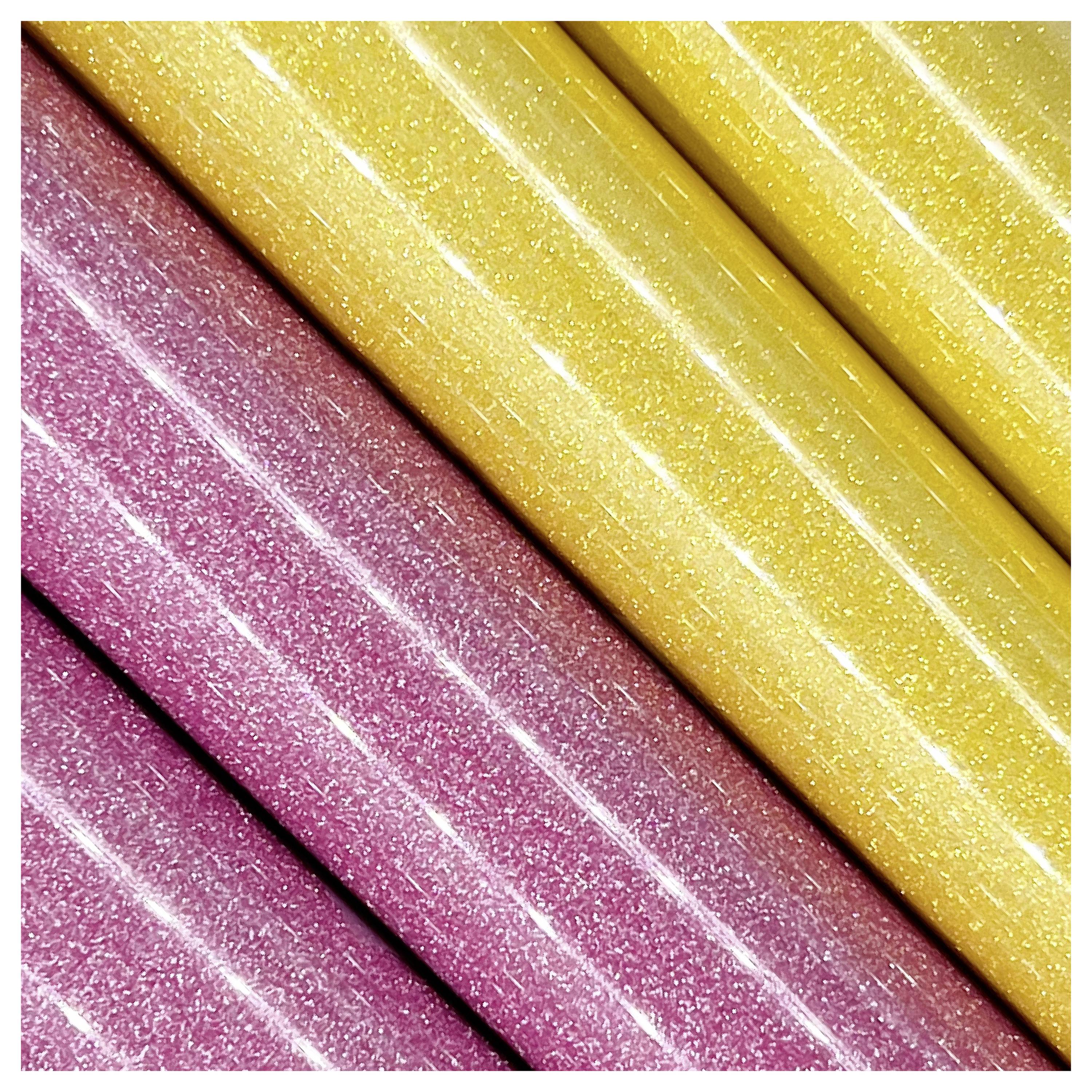 Nahaufnahme von glitzernden rosa und gelben strukturierten Oberflächen in diagonalen Reihen, die schimmernde Details und lebendigen Farbkontrast zeigen.