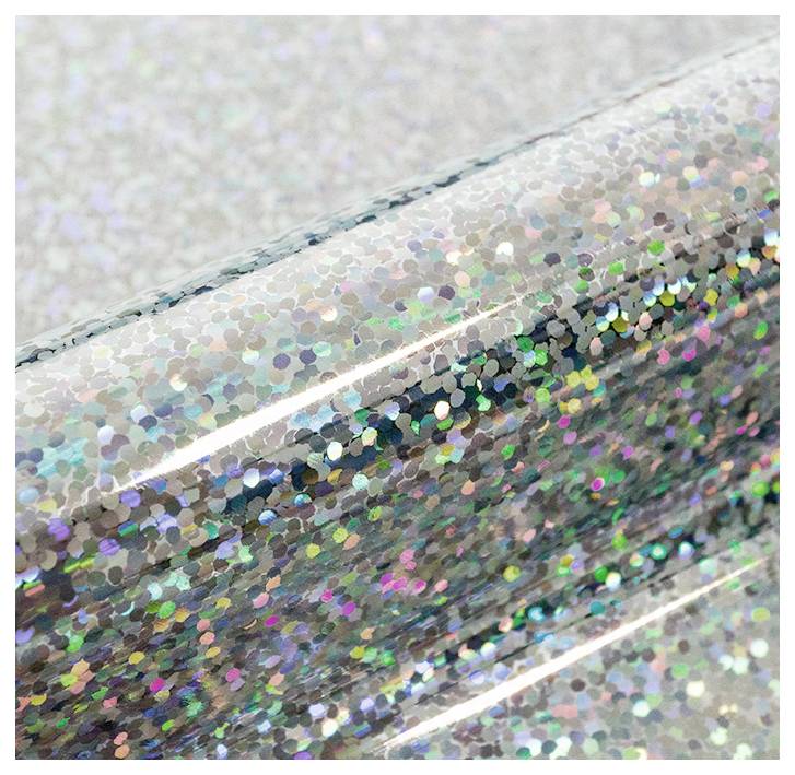 Nahaufnahme von farbenfrohem holografischem Glittervinyl im Licht, das ein schimmerndes Farbspektrum über eine strukturierte Oberfläche zeigt.