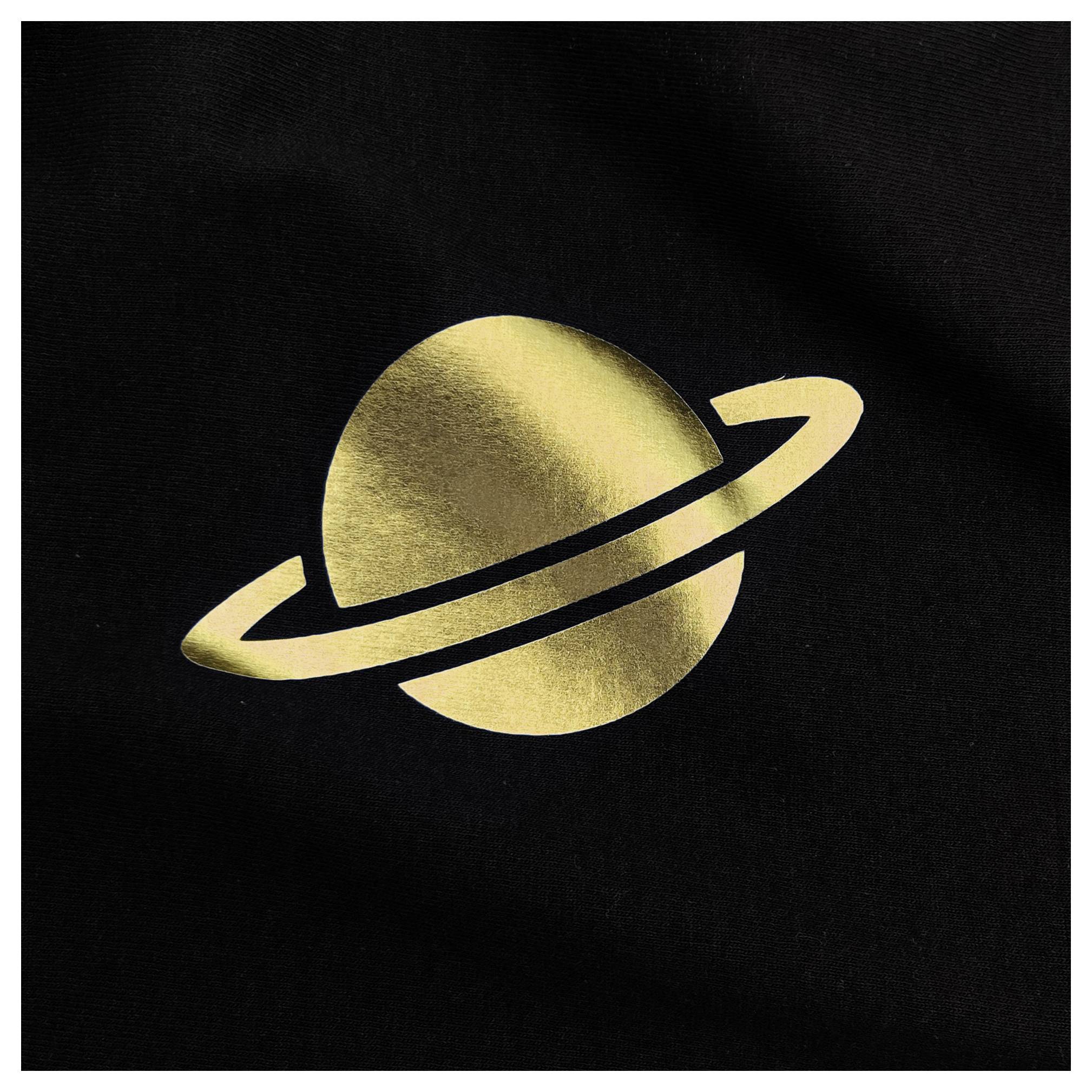 Eine goldene Silhouette eines Planeten mit Ringen, der dem Saturn ähnelt, auf schwarzem Hintergrund.
