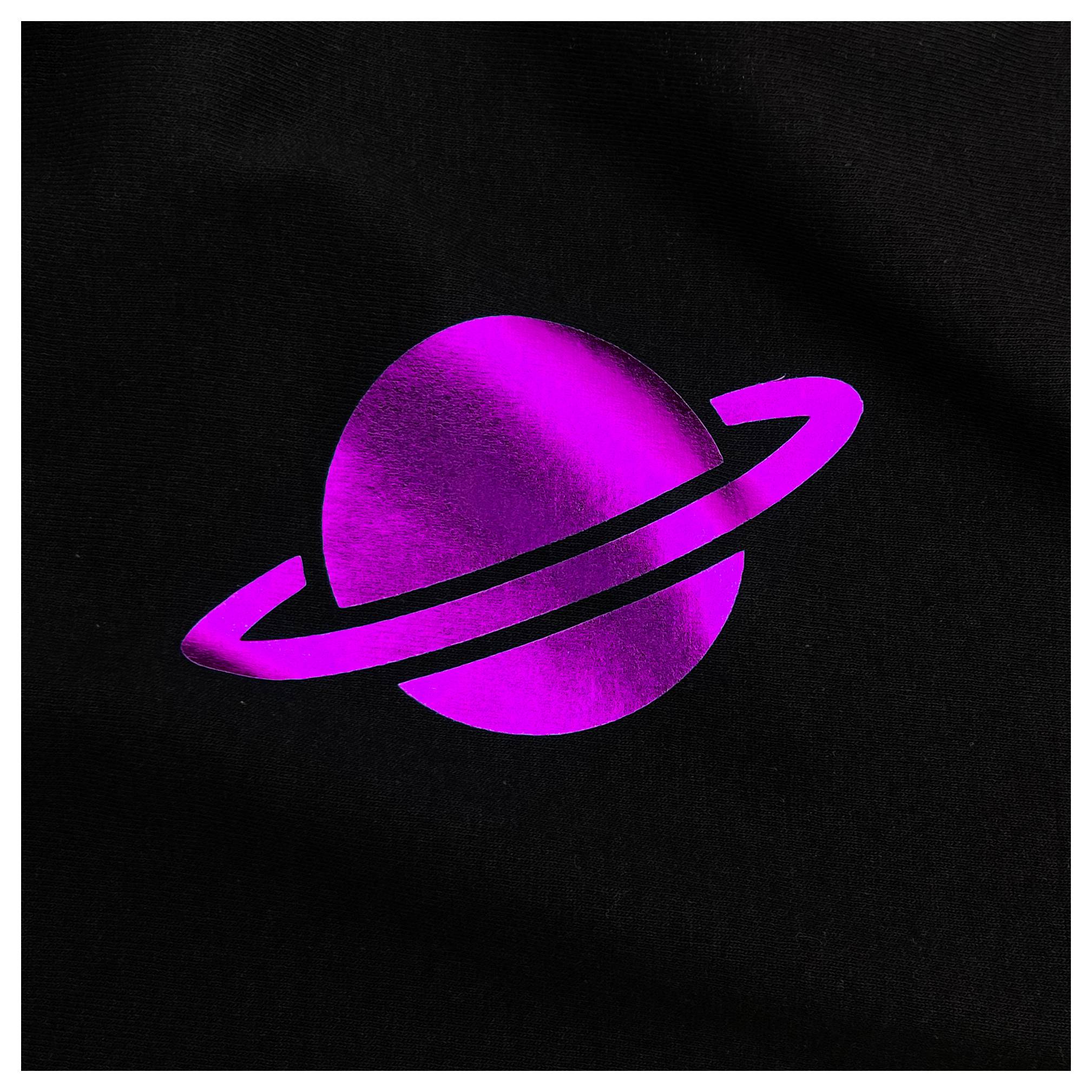 Ein glänzender rosa Planet mit einem Ring, der Saturn ähnelt, vor schwarzem Hintergrund.